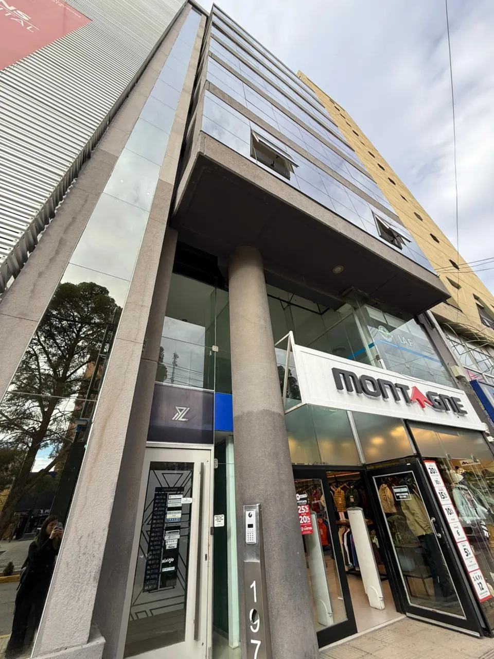 Detalle de la entrada del edificio de oficinas en Av. Argentina 197, 3° B, Neuquén, mostrando el poste con el número y el local de Montagne.